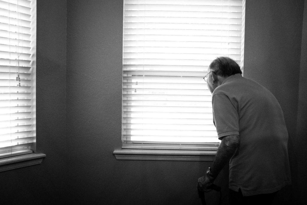 老人が窓の外を眺めている画像