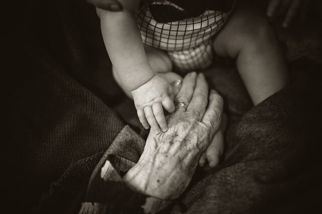 高齢者の手を握る幼児の手の画像